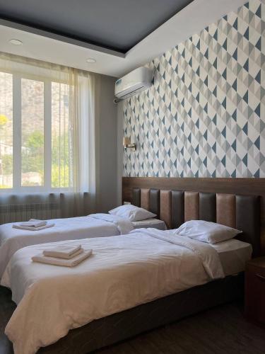two beds in a bedroom with a checkered wall at Prime LIDER COMPLEX Hotel in VAYK Town in Vaykʼ