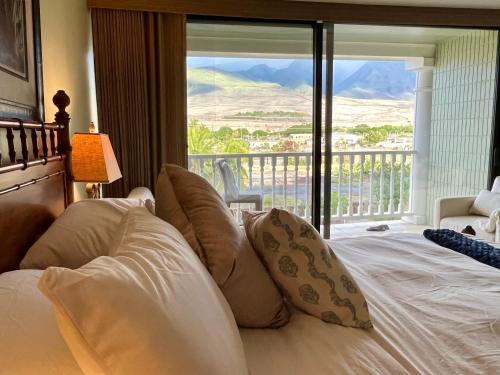 a bedroom with a bed and a balcony with a view at Compass Blue Lahaina in Lahaina