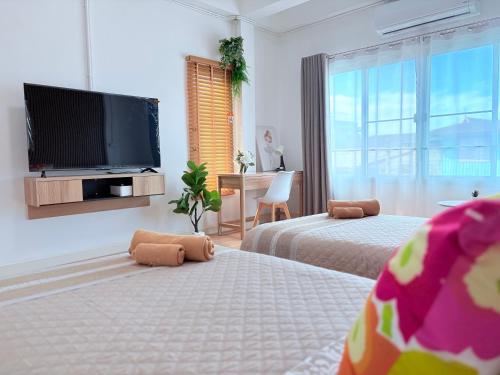 a bedroom with two beds and a flat screen tv at Na KlongMuang I ณ คลองเมือง in Phra Nakhon Si Ayutthaya