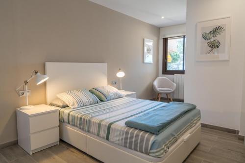 a bedroom with a bed and a desk and a window at SeaHomes Vacations - Cala Banys Seafront Apt & PKG in Lloret de Mar