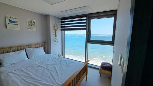 a bedroom with a bed and a view of the ocean at Charman Ocean View Sunrise 10 seconds to the beach in Kwangan-dong