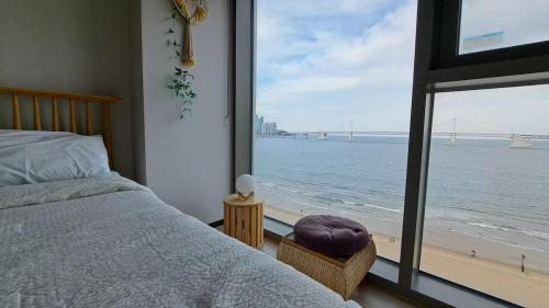 a bedroom with a bed and a view of the ocean at Charman Ocean View Sunrise 10 seconds to the beach in Kwangan-dong