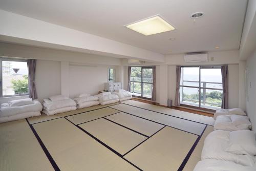 a living room with white furniture and large windows at Tobi Hostel and Apartments in Shima
