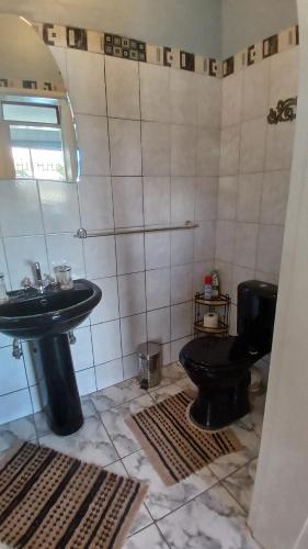 a bathroom with a black toilet and a sink at John-Lou's One-bedroom Apartment in Windhoek