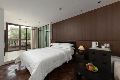 a bedroom with a large white bed and a table at Floral Hotel Gaosheng in Zhangzhou