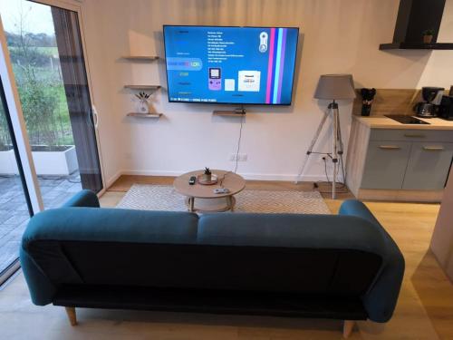 un salon avec un canapé bleu et une télévision dans l'établissement Loft chic avec Jacuzzi, à Plumergat