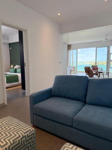 a living room with a blue couch and a bedroom at Lorlagon 2-Bedroom Beachfront Apartment by LOV Mauritius in Trou d'Eau Douce
