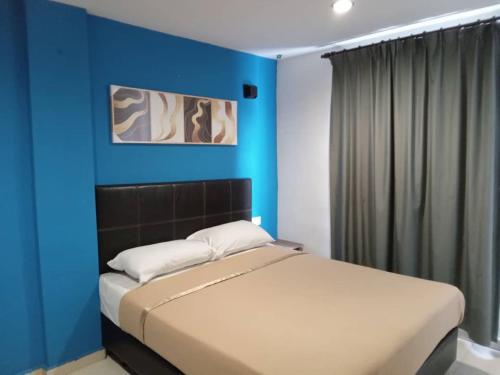 a bedroom with a blue wall and a bed at Vitro Hotel in Johor Bahru