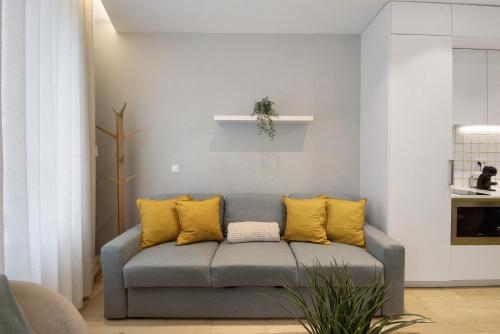 ein Wohnzimmer mit einem grauen Sofa und gelben Kissen in der Unterkunft T1 Moliceiros Centro de Aveiro in Aveiro