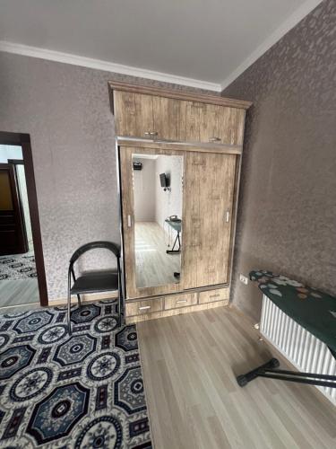 einen Spiegel in einem Zimmer mit einem Bett und einem Stuhl in der Unterkunft Уютная 2-х комнатная квартира 82м2 в Центре города! in Buxoro