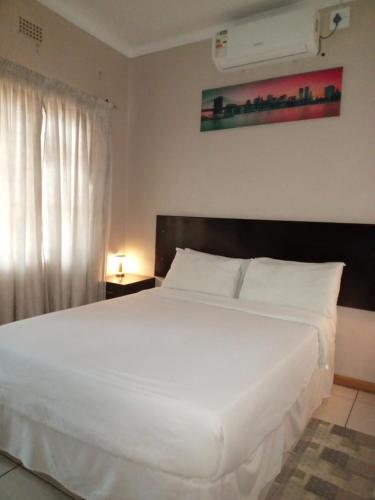 a bedroom with a large white bed with a window at Vuya Nathi Bed and Breakfast in Manzini