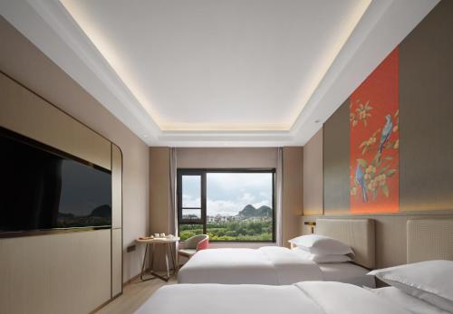 Un dormitorio con tres camas y una gran ventana. en Yicheng Hotel Guilin Liangjiang Sihu East-West Alley Branch, en Guilin