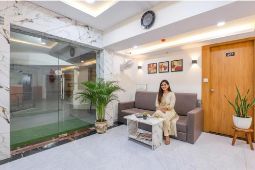 a woman sitting on a couch in a lobby at FabHotel Crystal I - Gandhinagar in Gandhinagar
