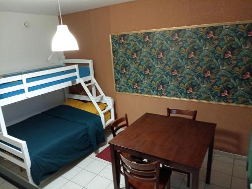 a small room with a bunk bed and a table at Ti'Kratèr Chambres d'hôtes in Le Tampon