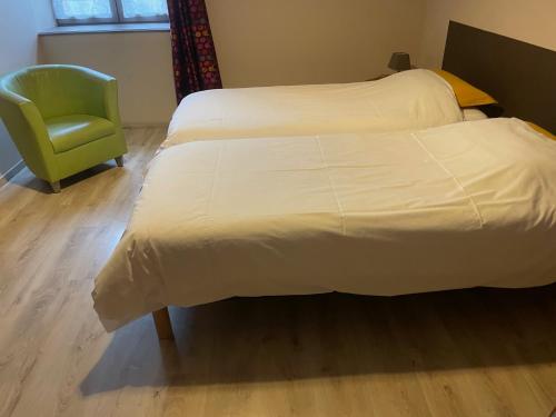 a bedroom with two beds and a green chair at La maison du vigneron in Ternand