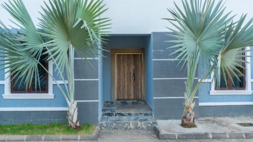 a blue house with two palm trees in front of it at Camp Ground 