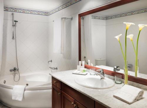 a bathroom with a white tub and a sink and a bath tub at Hotel Las Águilas Tenerife, Affiliated by Meliá in Puerto de la Cruz