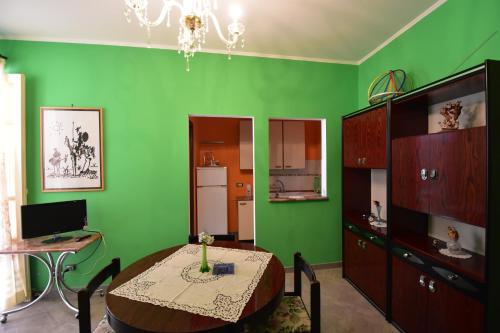 a dining room with a table and a green wall at AFFITTI BREVi in Palermo