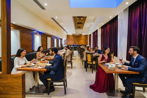 a group of people sitting at tables in a restaurant at FabHotel Devanshi Inn in Kalamboli