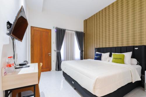 a bedroom with a bed and a desk and a television at Urbanview Hotel Brodam's Pematang Siantar by RedDoorz in Pematangsiantar