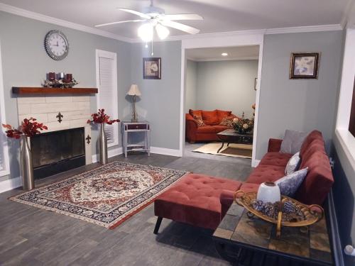 ein Wohnzimmer mit einem roten Sofa und einem Kamin in der Unterkunft The Denham Springs Esape- Pool, Comfort & Charm in Denham Springs