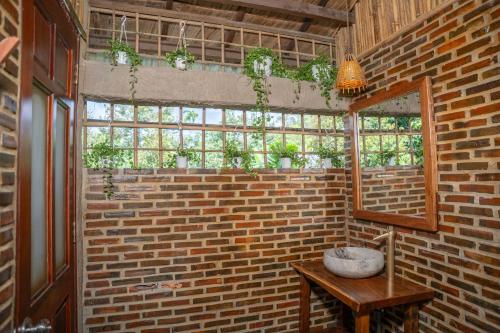 a room with a brick wall with a table and a mirror at Vamxang Rustic Home in Can Tho
