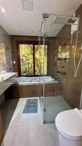 a bathroom with a shower and a toilet and a tub at Praia do Forte - Mansão Sunset in Mata de Sao Joao
