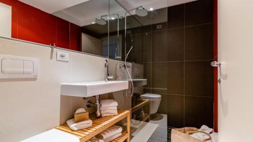 a bathroom with a sink and a toilet and red cabinets at Modernes Apartment - Nockberge in Ebene Reichenau