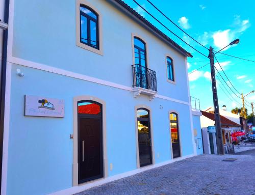 a white building with a black door on a street at Pinhal Litoral in Marinha Grande