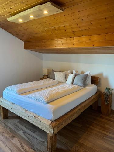 a large bed in a room with a wooden ceiling at Castle and Alps Appartement in Halblech