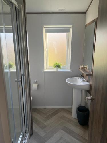 a bathroom with a sink and a mirror and a window at NEW 2025 Modern 3Bedrooms Lodge Walk to Beach in Morecambe