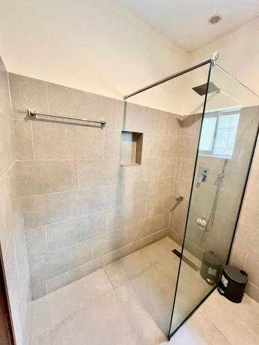 eine Dusche mit Glastür im Badezimmer in der Unterkunft Elegant Studio Haven Offering Peace, Comfort & Style in Mama