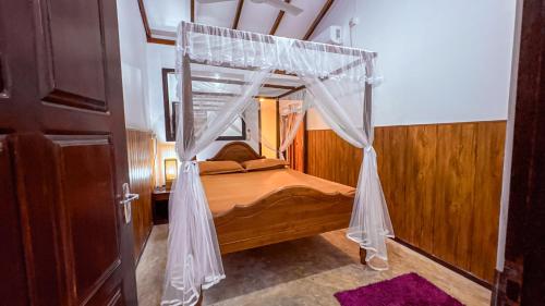 ein Schlafzimmer mit einem Holzbett mit Baldachin in der Unterkunft Samudura Beach House, Owakanda in Ratgama Hegoda