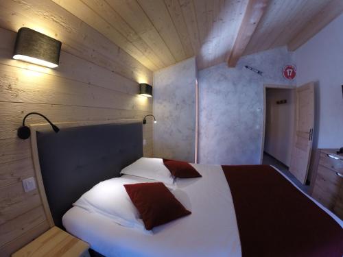 a bedroom with a white bed with two pillows on it at Hôtel Les Côtes, Résidence Loisirs et Chalets in Morzine