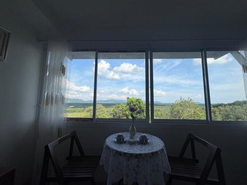 a table with a vase of flowers in a room with a window at BaanPhutawanLanta in Ban Mo Nae