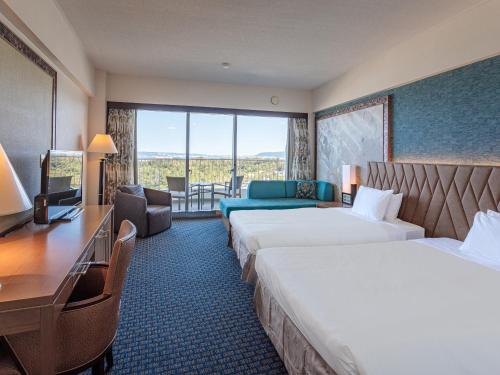 a hotel room with two beds and a desk at Okinawa Kariyushi Beach Resort Ocean Spa in Onna