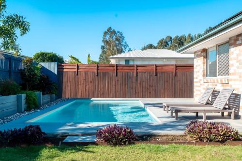 a swimming pool in a backyard with a wooden fence at Cozy 4BR House in Coomera - with Pool and parking in Gold Coast