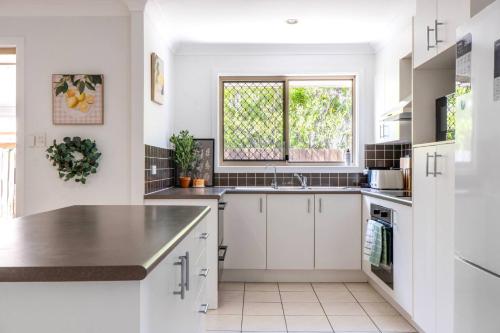 a white kitchen with a sink and a window at Cozy 4BR House in Coomera - with Pool and parking in Gold Coast