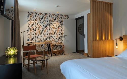 a hotel room with a bed and a table and chairs at Logis Hôtel et Restaurant La Pension du Moulin in Pont-Aven