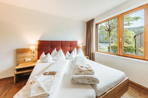 a bedroom with a bed with white sheets and a window at Regitnig - 4 Sterne Hotel und Chalets in Weissensee