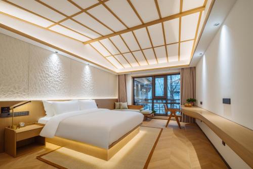 une chambre avec un grand lit blanc dans une pièce dans l'établissement Huazhu Luxury Niushou Yinlan Homestay, à Sanbanqiao