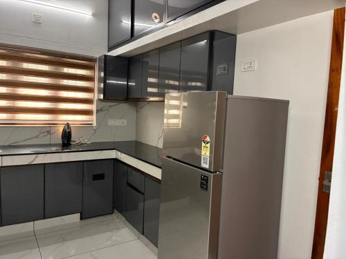 a kitchen with a stainless steel refrigerator and black cabinets at Prasadam Inn Varkala in Varkala