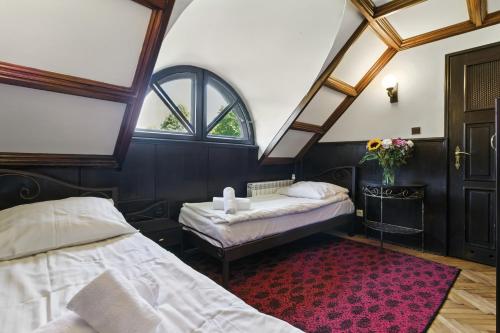 Camera mansardata con 2 letti e tappeto rosso. di Dwór Rychwałd a Rychwałd