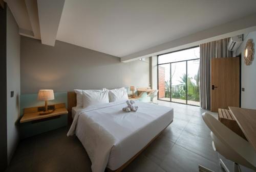 una camera da letto con un letto bianco e una grande finestra di Umahan Ubud ad Ubud