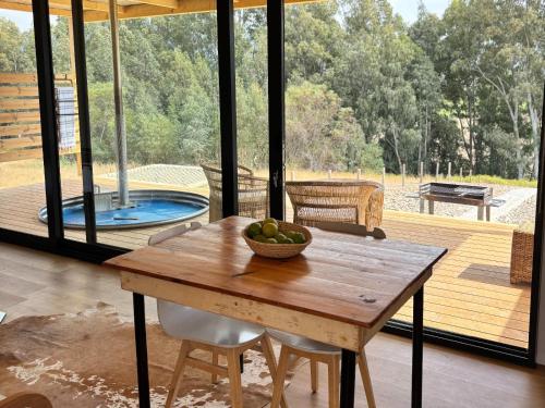 einen Holztisch mit einer Obstschale auf einer Terrasse in der Unterkunft Arendsig Wine Estate and River Eco Cabin in Bonnievale