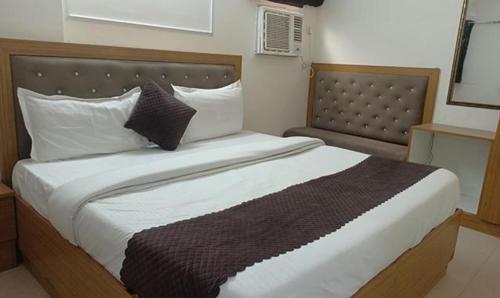 een slaapkamer met een groot bed met een houten hoofdeinde bij FabHotel The Rivlet Centre in New Delhi