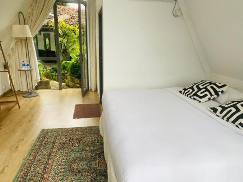 ein weißes Bett in einem Zimmer mit Fenster in der Unterkunft Rain Drops Wellness Villa in Mederipitiya