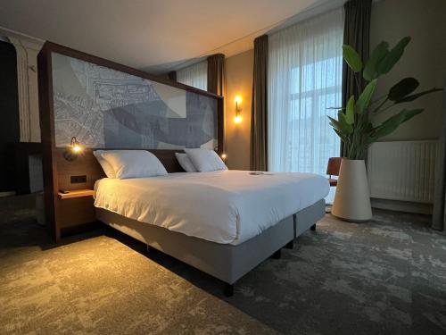 a bedroom with a large bed and a large window at Fletcher Hotel Paleis Stadhouderlijk Hof in Leeuwarden