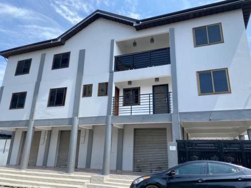 a white house with a car parked in front of it at Nick Jaaks Courtyard-Single Room in Accra