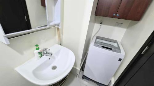 a small bathroom with a sink and a dispenser at City View with Balcony at Kasara Residences C5 Pasig in Manila